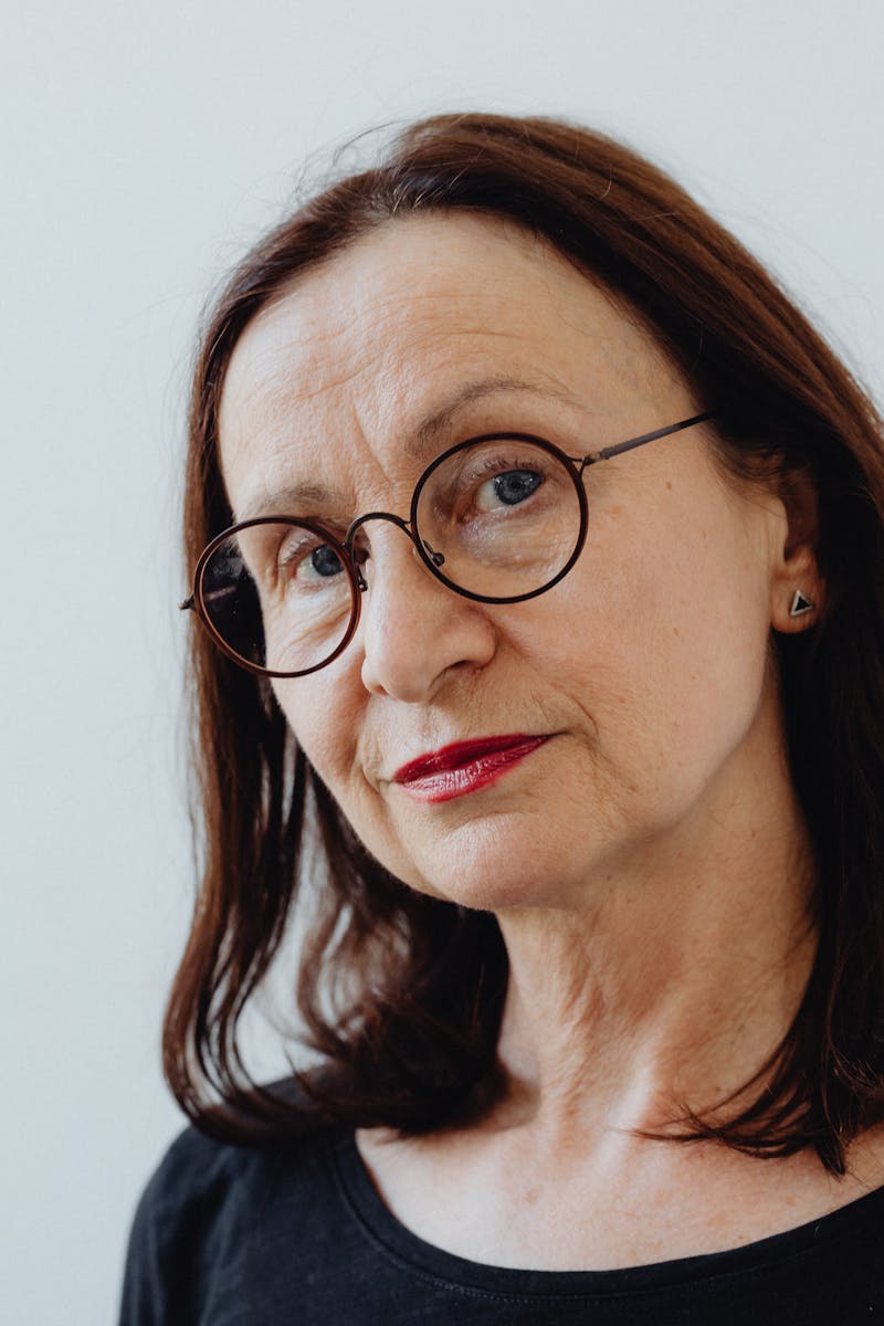 Captivating portrait of an older woman with eyeglasses and a thoughtful expression.